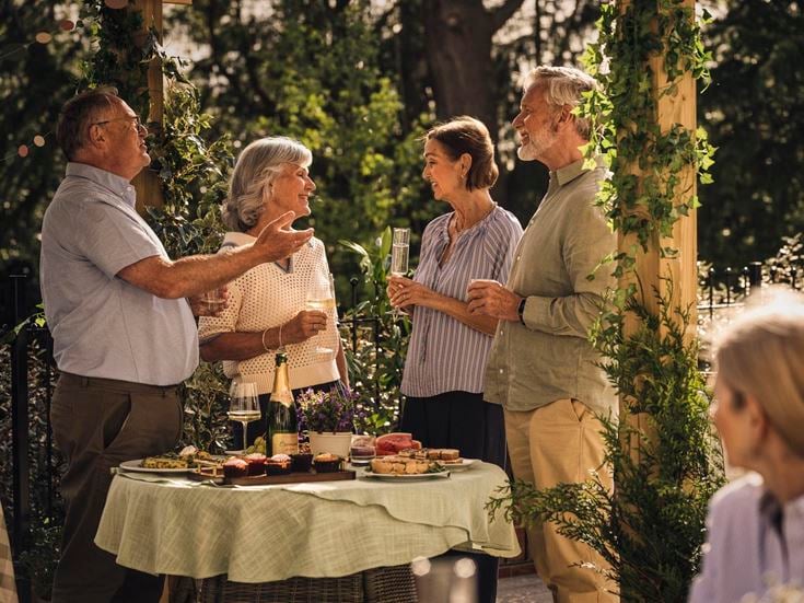 a group of people standing around a table with food and drinks