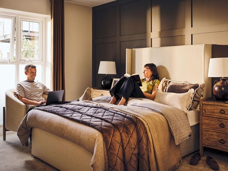 a man and a woman sitting on a bed with a laptop