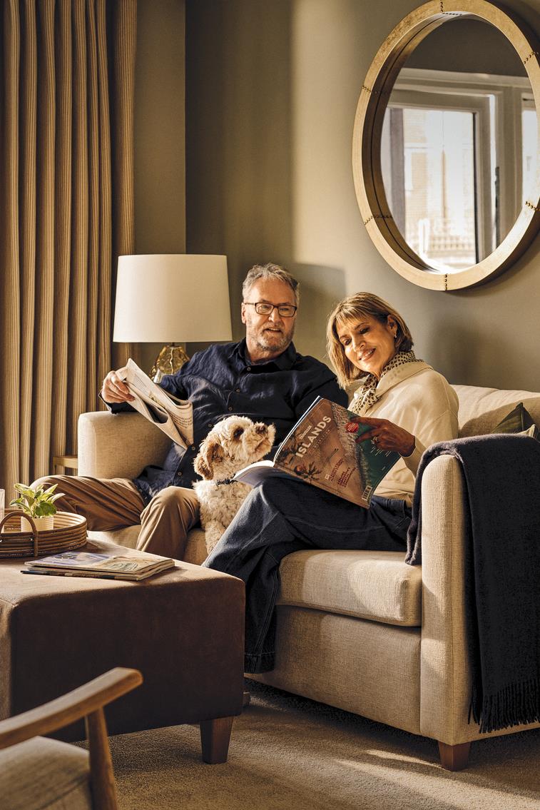a man and woman sitting on a couch with a dog